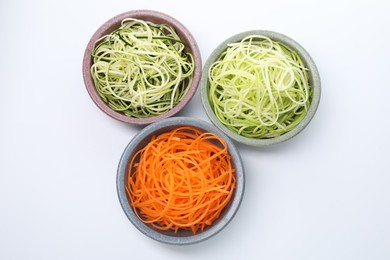 Photo of Different vegetable noodles in bowls isolated on white, top view. Vegetarian dish