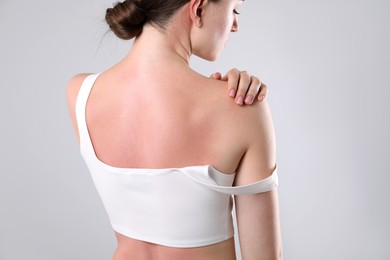 Photo of Woman with sunburned skin on grey background, back view