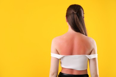 Photo of Woman with sunburned skin on orange background, back view. Space for text