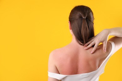 Photo of Woman with sunburned skin on orange background, back view. Space for text