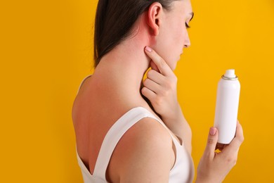 Photo of Woman with sunburned skin holding bottle of sun protection product on orange background, closeup