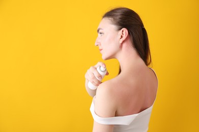 Photo of Woman applying sun protection product on her sunburned skin against orange background, space for text