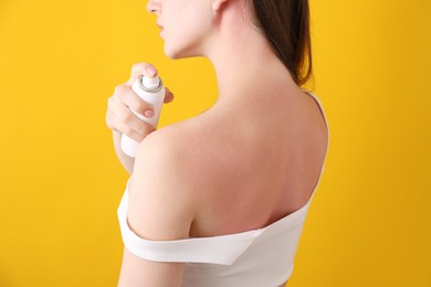 Photo of Woman applying sun protection product on her sunburned skin against orange background, closeup