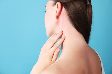Photo of Woman with sunburned skin on light blue background, closeup. Space for text