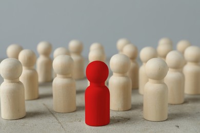 Image of Dismissal. Red figure among wooden ones on light table