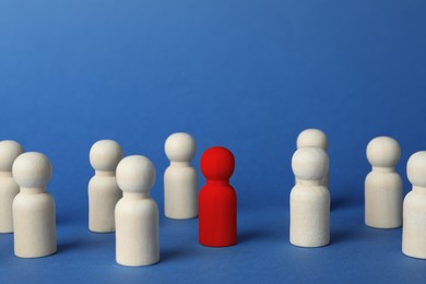 Image of Dismissal. Red figure among wooden ones on blue background
