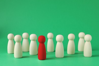 Image of Dismissal and unemployment. Red figure among wooden ones on green background