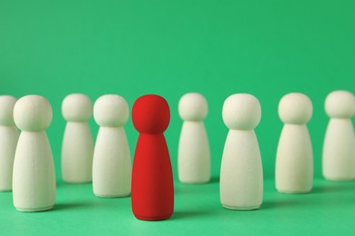 Image of Dismissal and unemployment. Red figure among wooden ones on green background