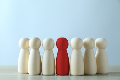 Image of Dismissal. Red figure among wooden ones on table