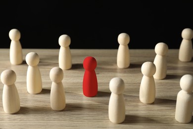 Image of Dismissal. Red figure among wooden ones on table