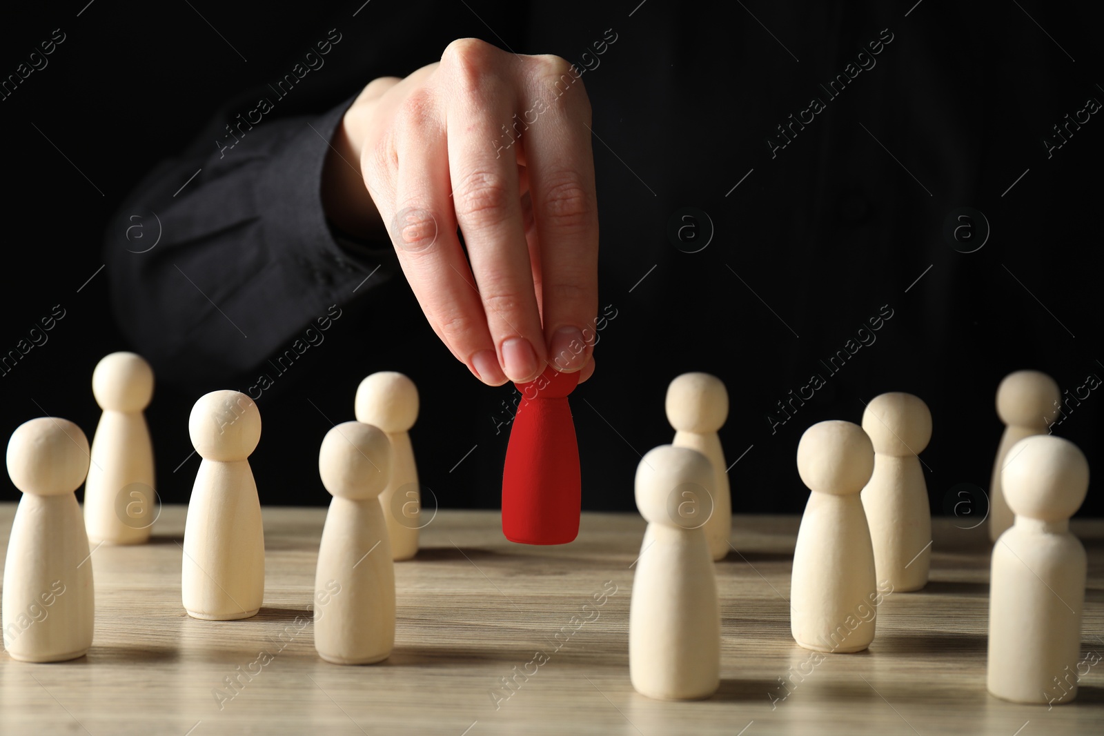 Dismissal. Woman choosing red figure among wooden ones at table, closeup Image of Dismissal. Woman choosing red figure among wooden ones at table, closeup