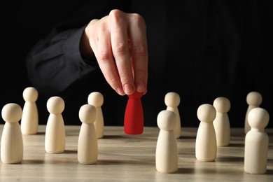 Image of Dismissal. Woman choosing red figure among wooden ones at table, closeup
