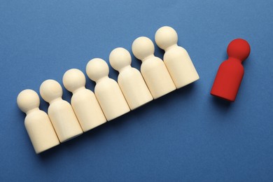 Image of Dismissal. Red figure lying apart among wooden ones on blue background, top view