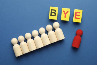 Image of Dismissal. Red figure lying apart among wooden ones and word Bye made with cards on blue background, top view