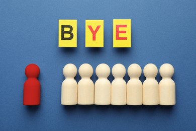 Image of Dismissal. Red figure lying apart among wooden ones and word Bye made with cards on blue background, top view