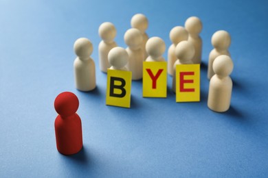 Image of Dismissal. Red standing in front wooden ones with word Bye made of cards on blue background