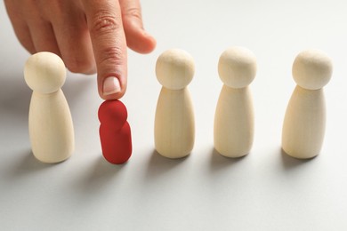 Image of Dismissal. Woman choosing red figure among wooden ones at white table, closeup