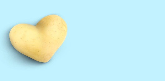 Image of Heart shaped potato on light blue background, top view. Banner design with space for text