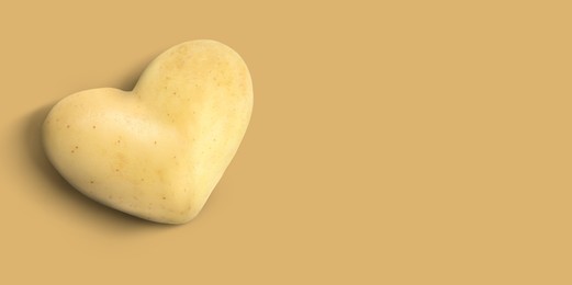 Image of Heart shaped potato on dark beige background, top view. Banner design with space for text