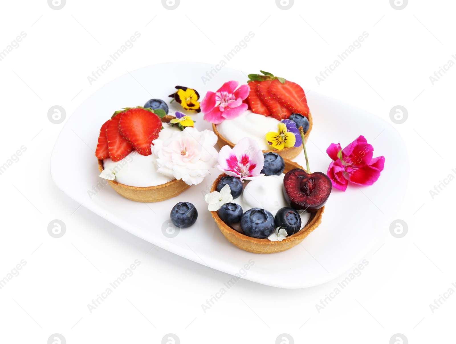 Photo of Sweet tartlets with berries and flowers isolated on white. Delicious dessert
