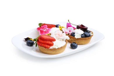Photo of Sweet tartlets with berries and flowers isolated on white. Delicious dessert