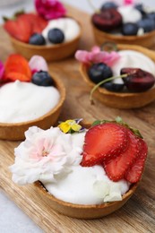 Photo of Sweet tartlets with berries and flowers on grey table, closeup. Delicious dessert