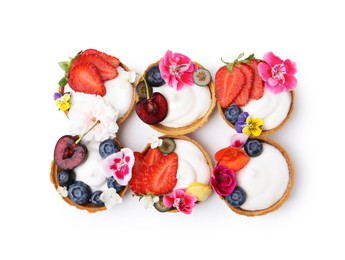 Photo of Sweet tartlets with berries and flowers isolated on white, top view. Delicious dessert