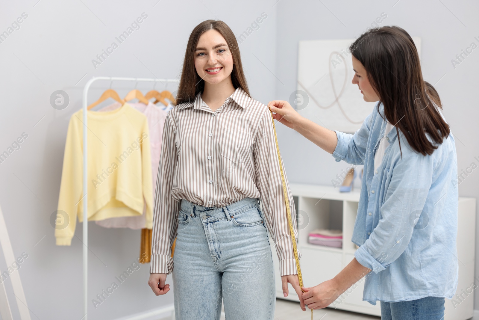 Tailor measuring woman's arm with tape in atelier Photo of Tailor measuring woman's arm with tape in atelier