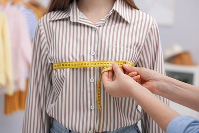 Photo of Tailor measuring woman's chest with tape in atelier, closeup