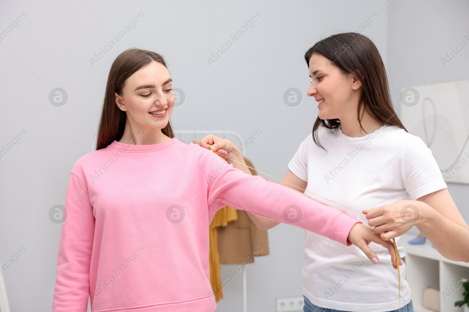Tailor measuring woman's arm with tape in atelier Photo of Tailor measuring woman's arm with tape in atelier