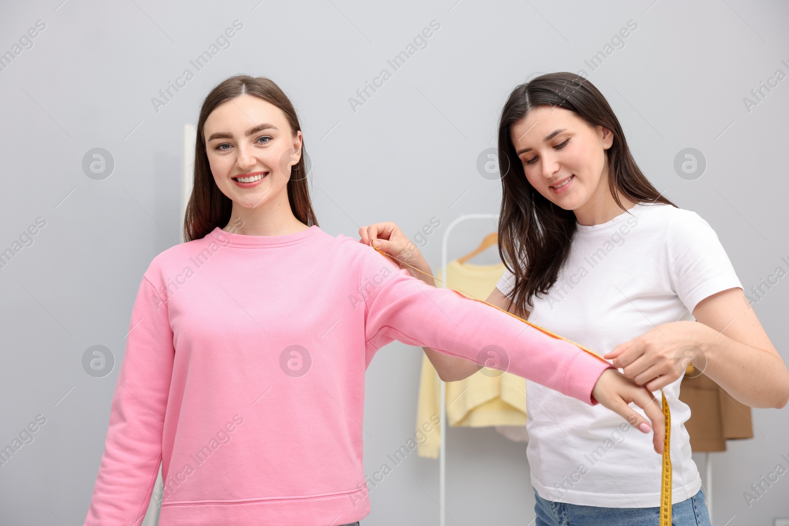 Tailor measuring woman's arm with tape in atelier Photo of Tailor measuring woman's arm with tape in atelier