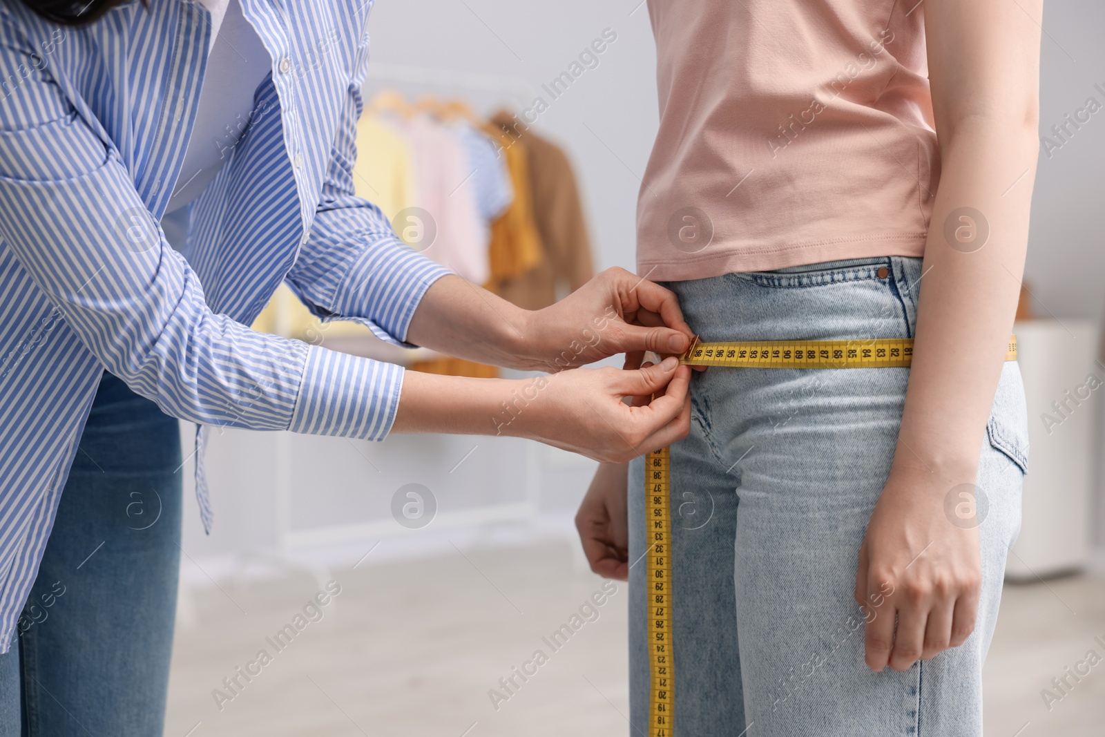 Tailor measuring woman's hips in atelier, closeup Photo of Tailor measuring woman's hips in atelier, closeup