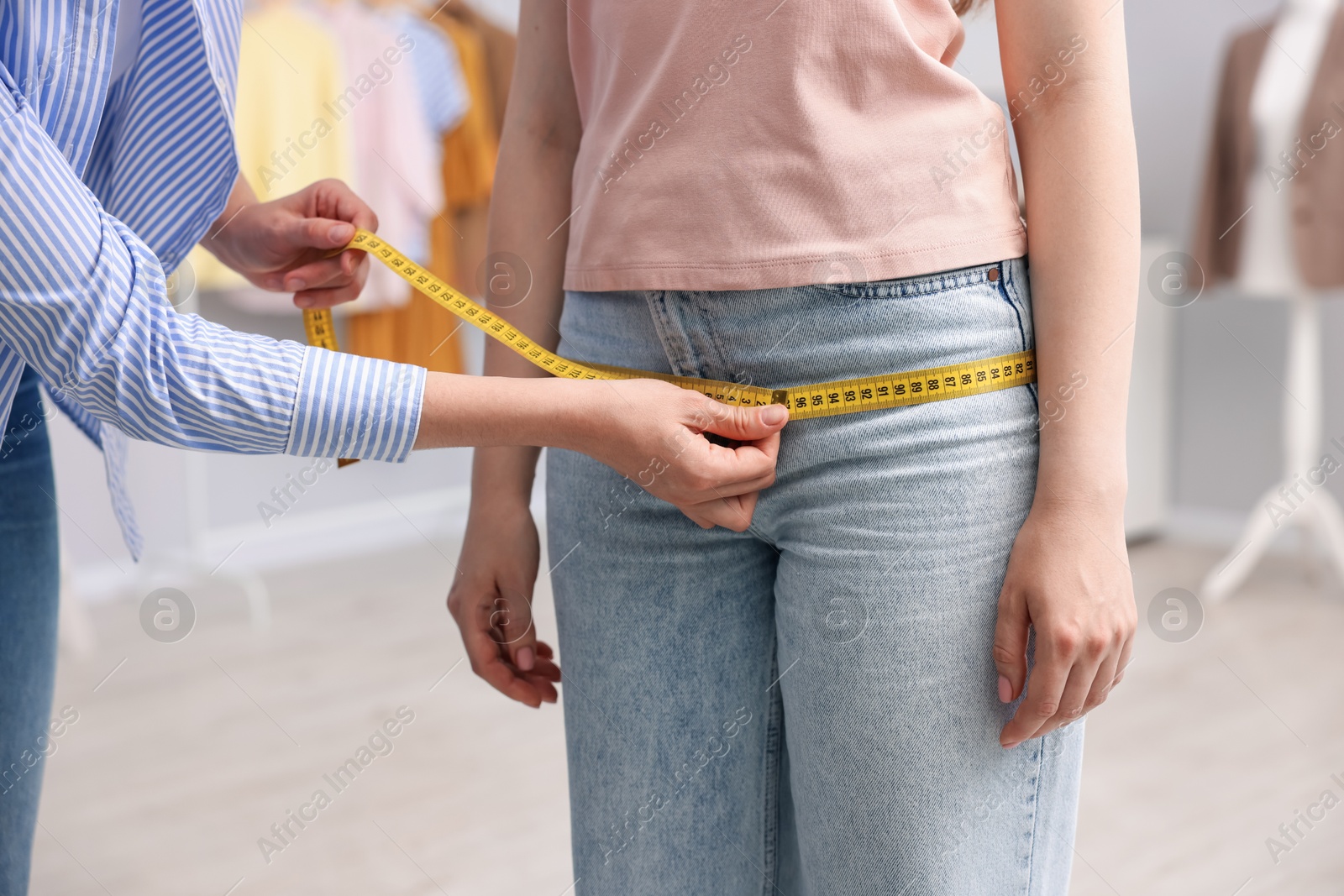Tailor measuring woman's hips in atelier, closeup Photo of Tailor measuring woman's hips in atelier, closeup