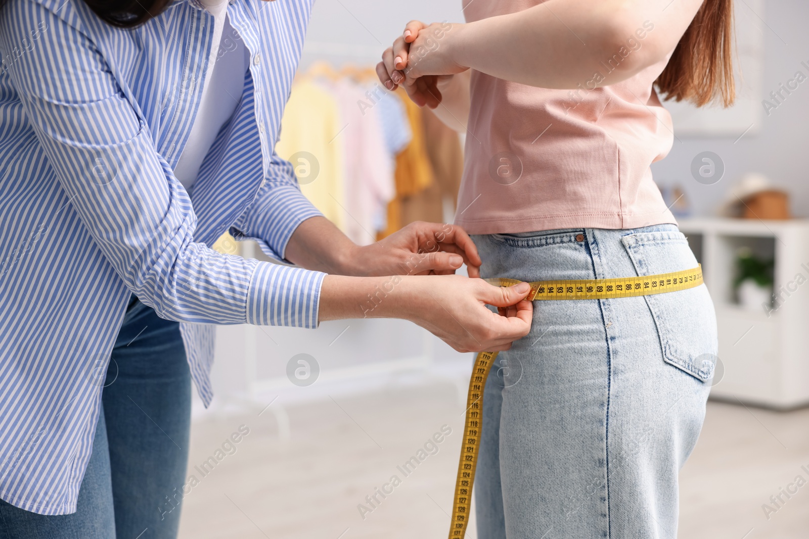 Tailor measuring woman's hips in atelier, closeup Photo of Tailor measuring woman's hips in atelier, closeup