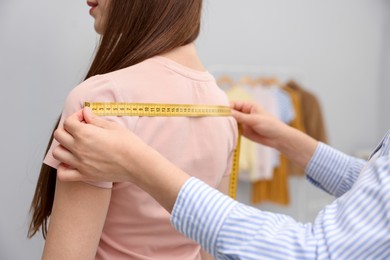 Photo of Tailor measuring woman's back in atelier, closeup