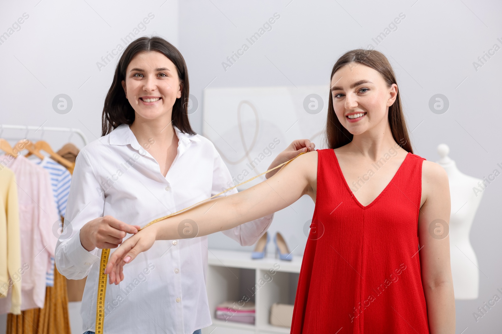 Tailor measuring woman's arm with tape in atelier Photo of Tailor measuring woman's arm with tape in atelier