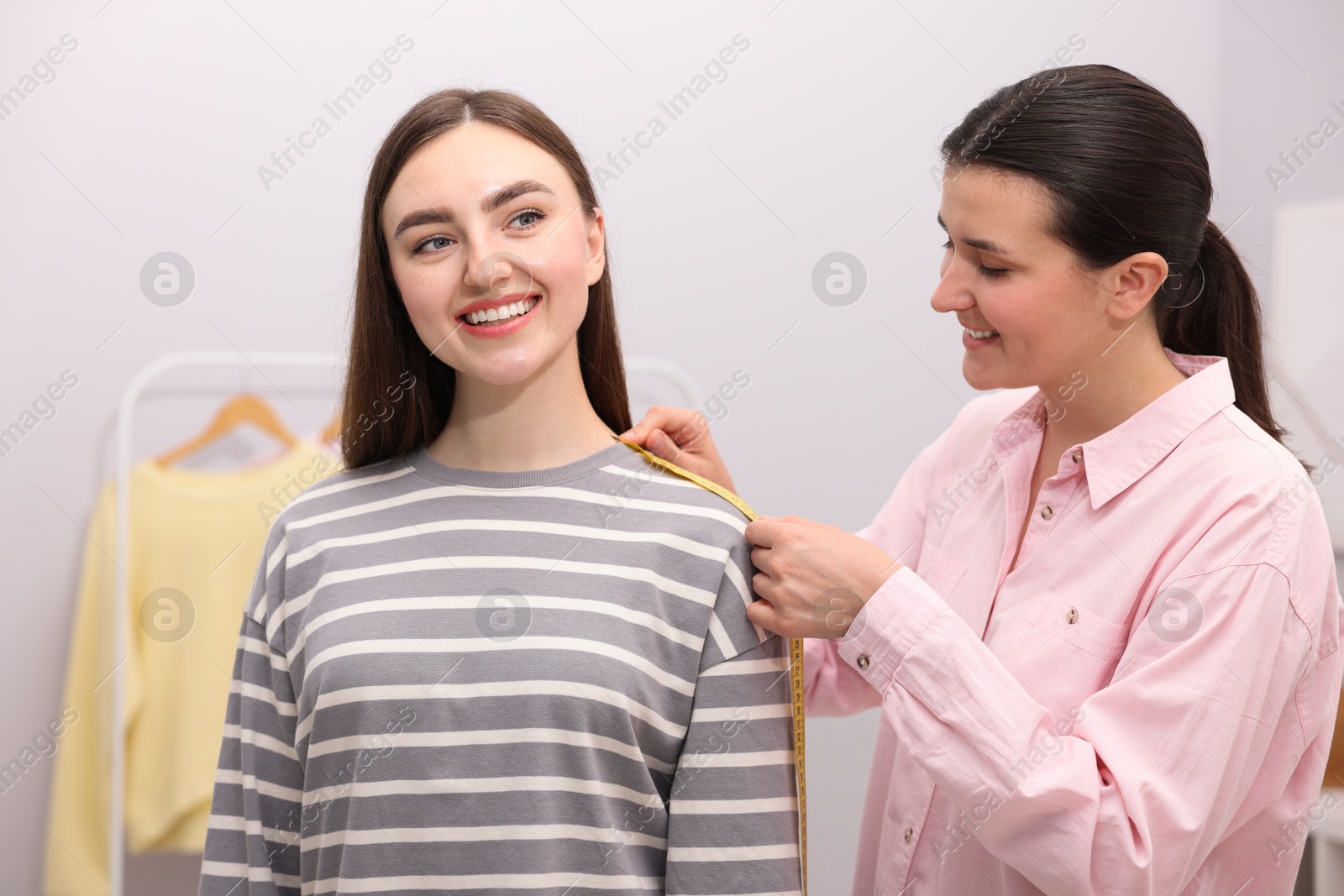Tailor measuring woman's shoulder with tape in atelier Photo of Tailor measuring woman's shoulder with tape in atelier