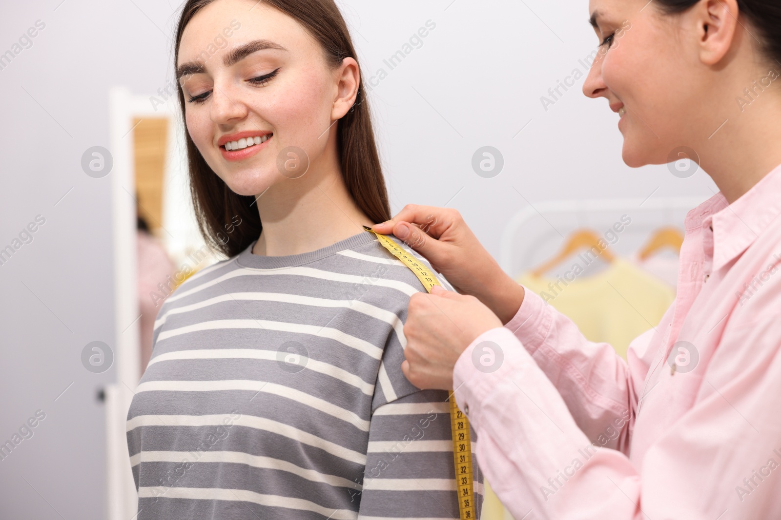 Tailor measuring woman's shoulder with tape in atelier Photo of Tailor measuring woman's shoulder with tape in atelier