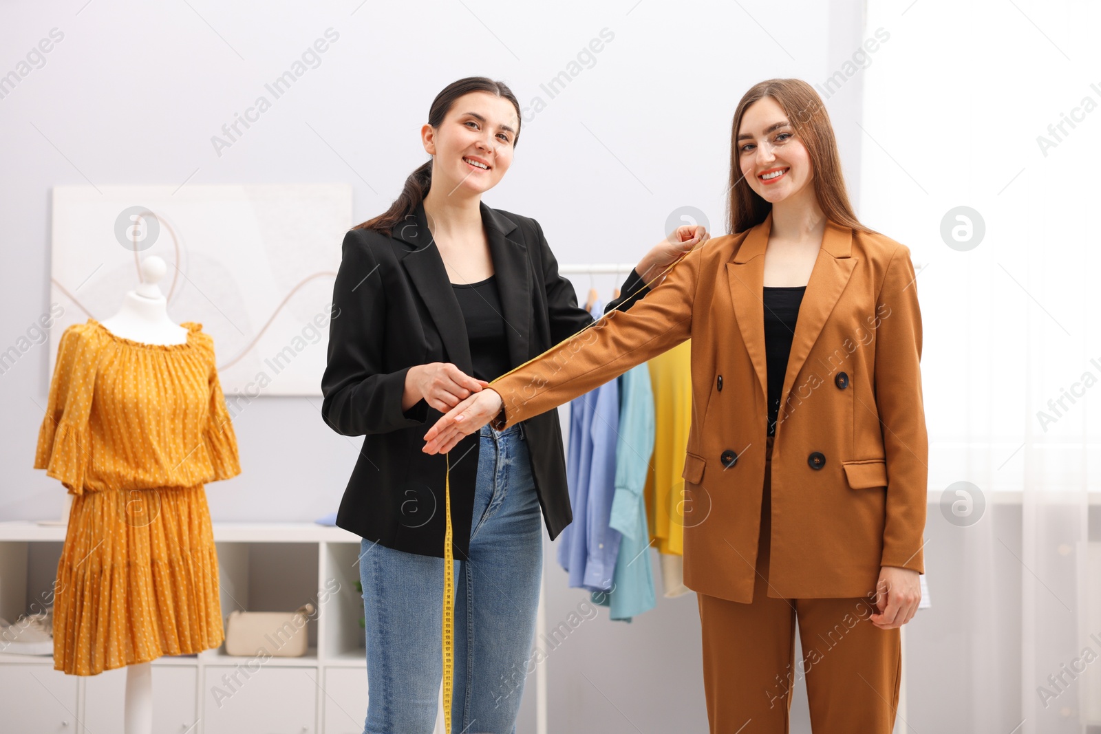 Photo of Tailor measuring jacket sleeve on woman in atelier