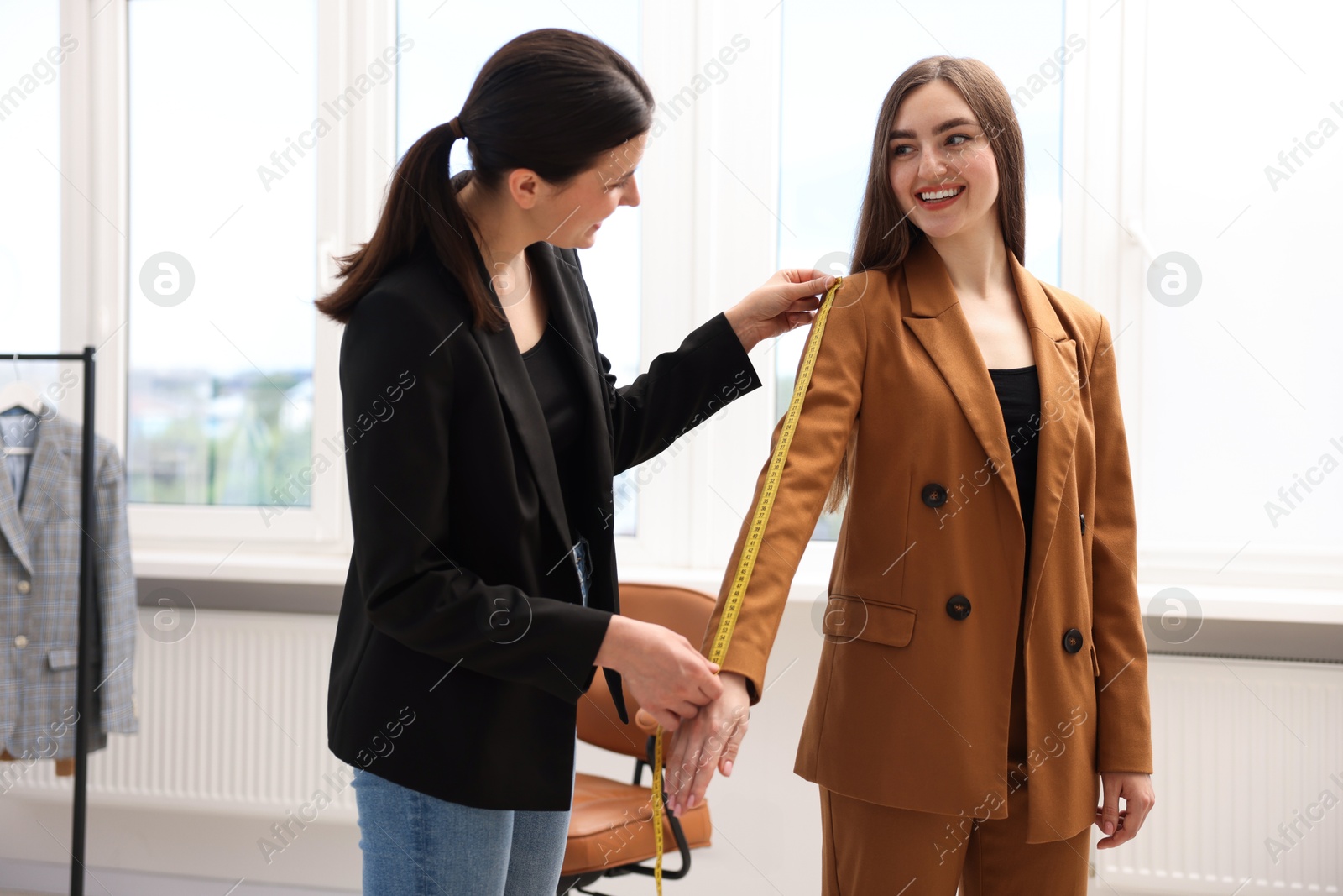 Tailor measuring jacket sleeve on woman in atelier Photo of Tailor measuring jacket sleeve on woman in atelier