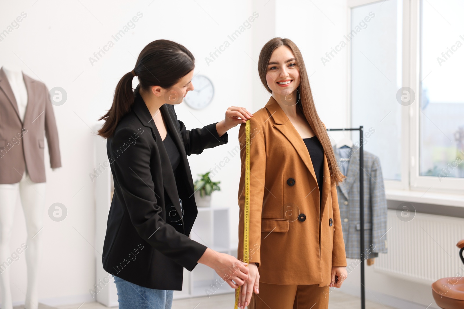 Tailor measuring jacket sleeve on woman in atelier Photo of Tailor measuring jacket sleeve on woman in atelier
