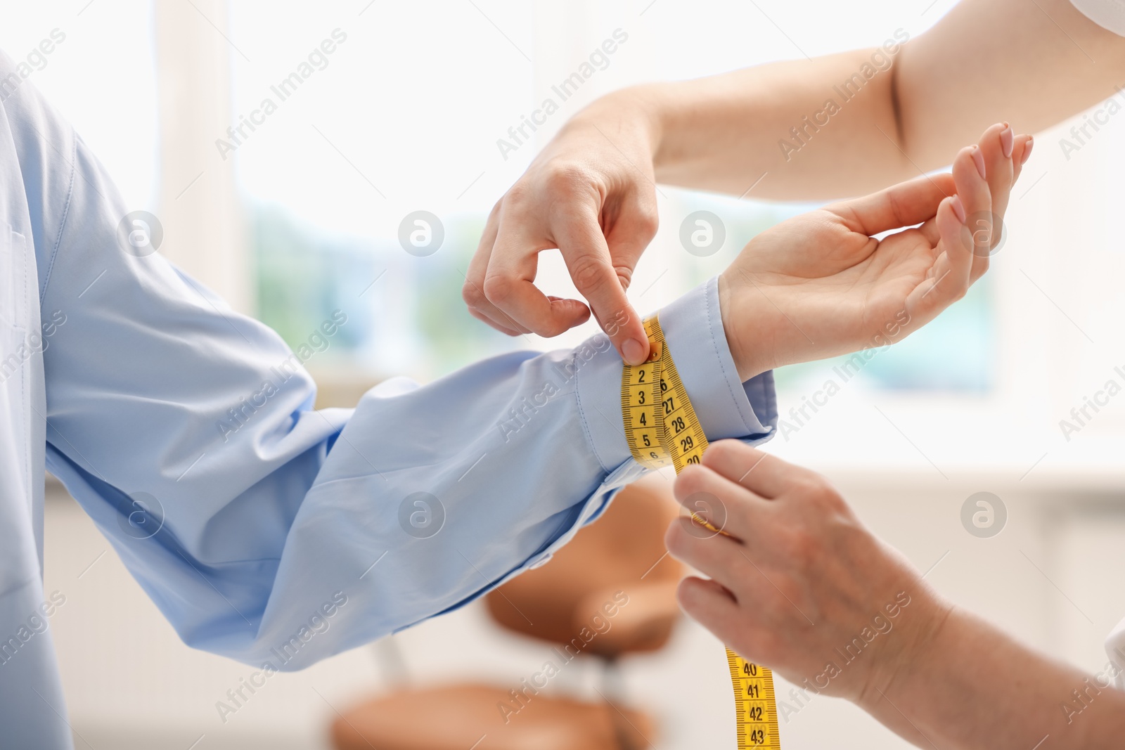Tailor measuring woman's wrist with tape in atelier, closeup Photo of Tailor measuring woman's wrist with tape in atelier, closeup