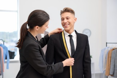 Photo of Tailor measuring jacket on man in atelier