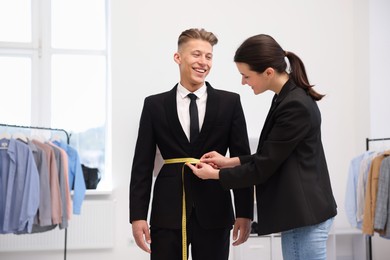 Photo of Tailor measuring jacket on man in atelier