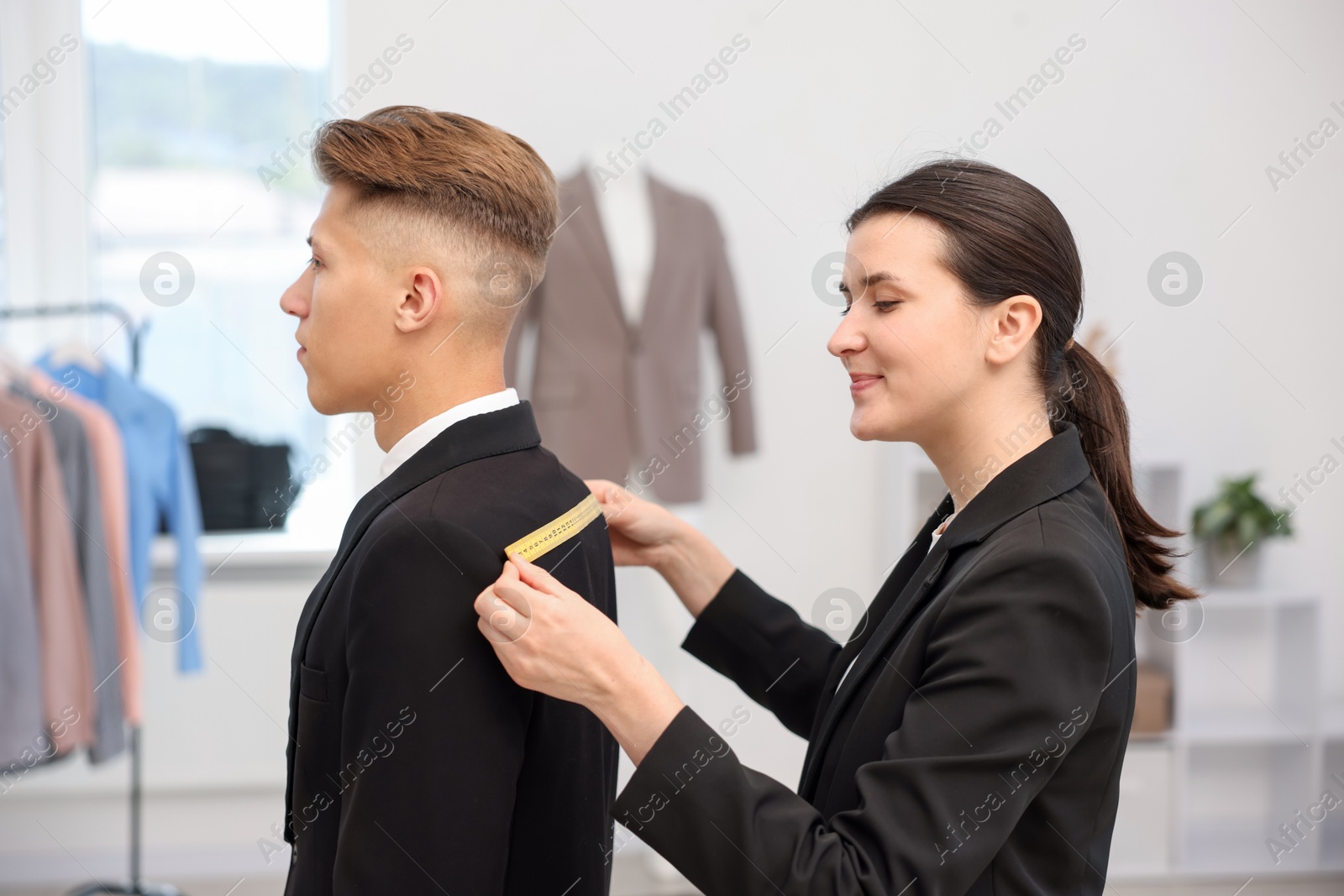 Photo of Tailor measuring jacket on man in atelier