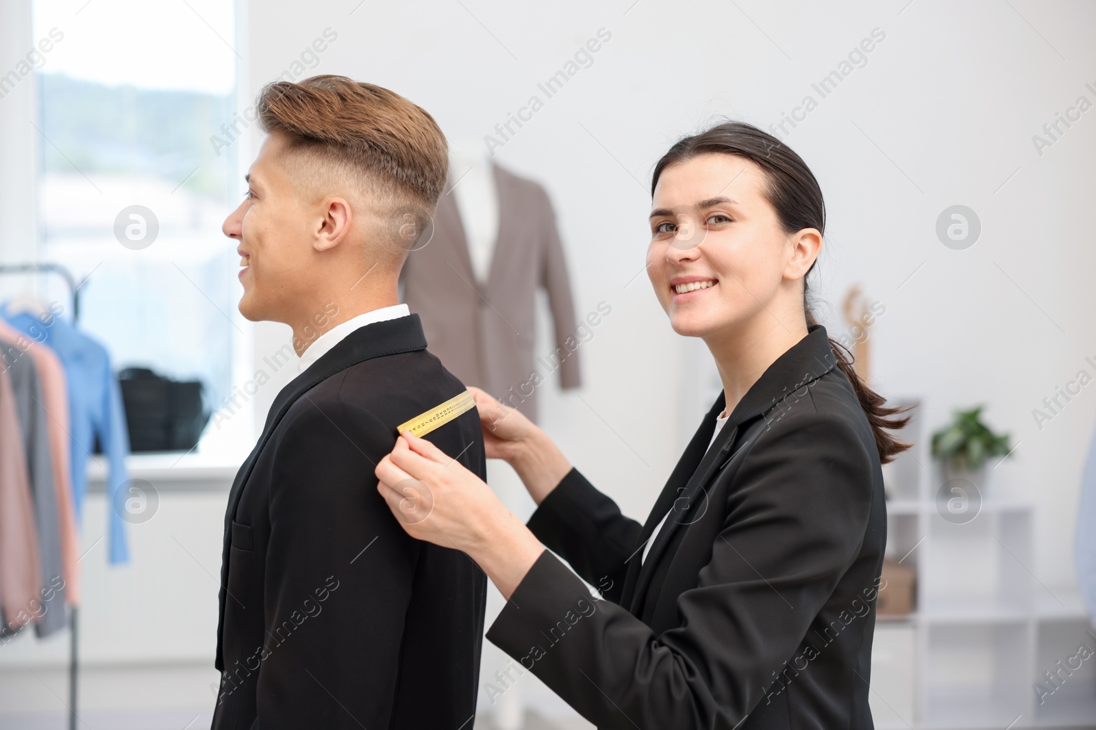 Photo of Tailor measuring jacket on man in atelier