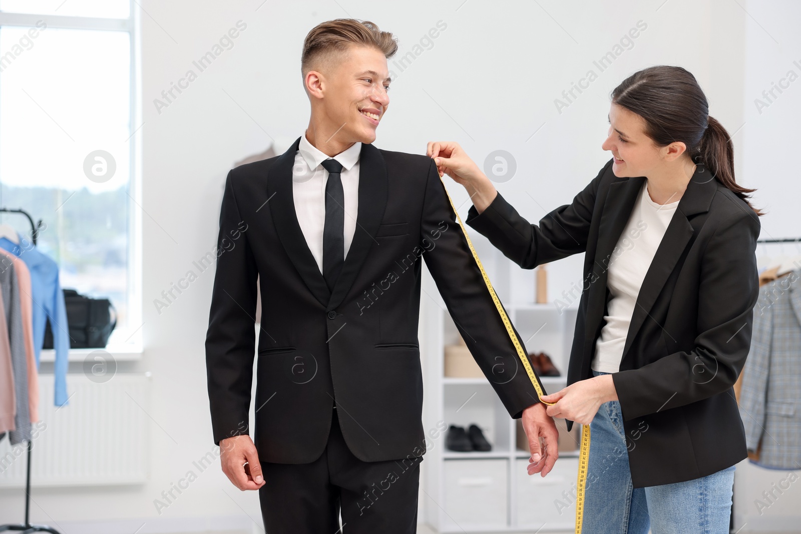 Photo of Tailor measuring jacket on man in atelier