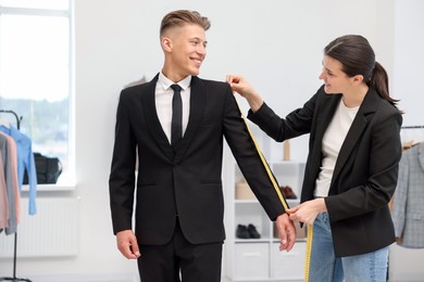 Photo of Tailor measuring jacket on man in atelier