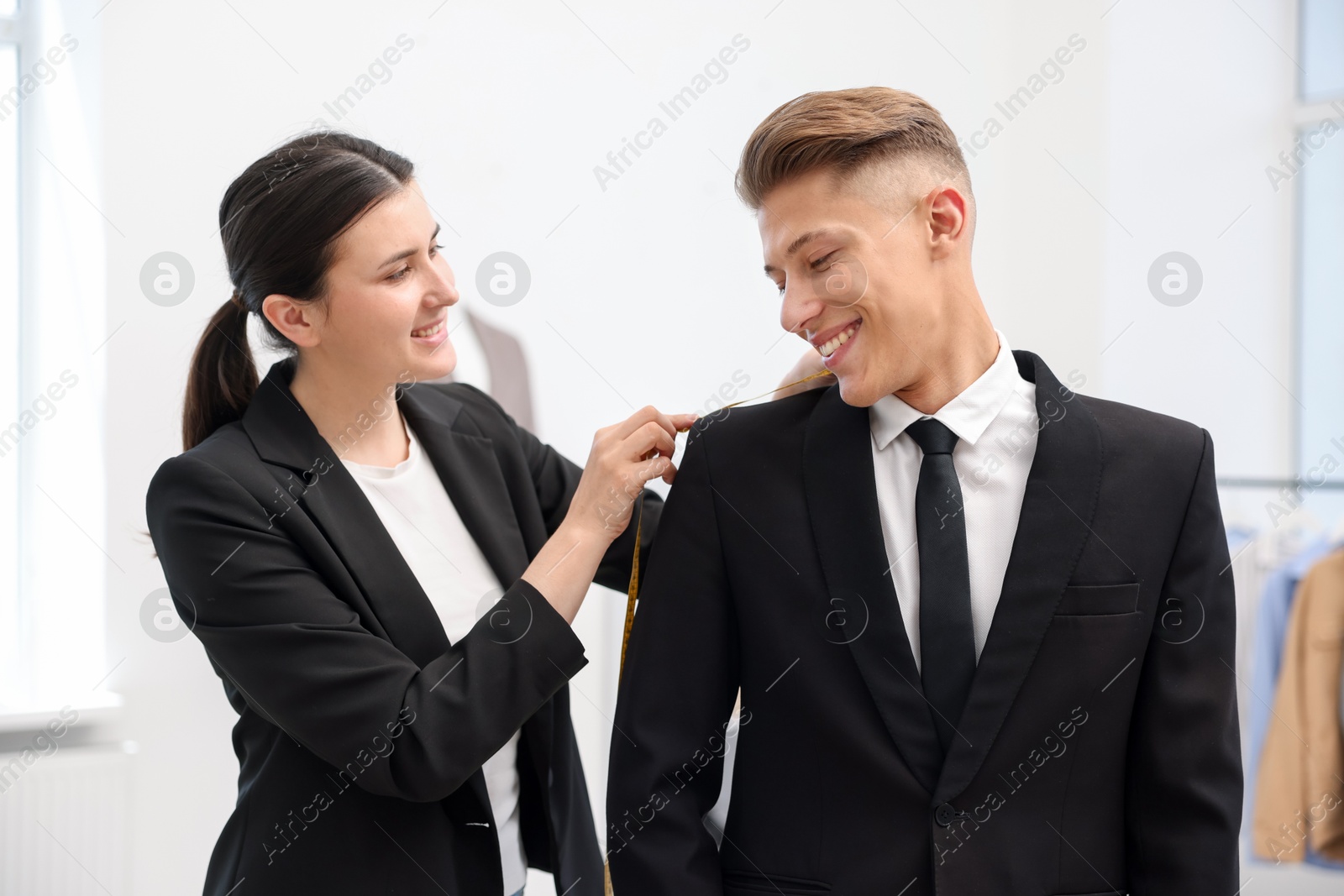Photo of Tailor measuring jacket on man in atelier