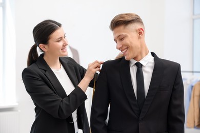 Photo of Tailor measuring jacket on man in atelier